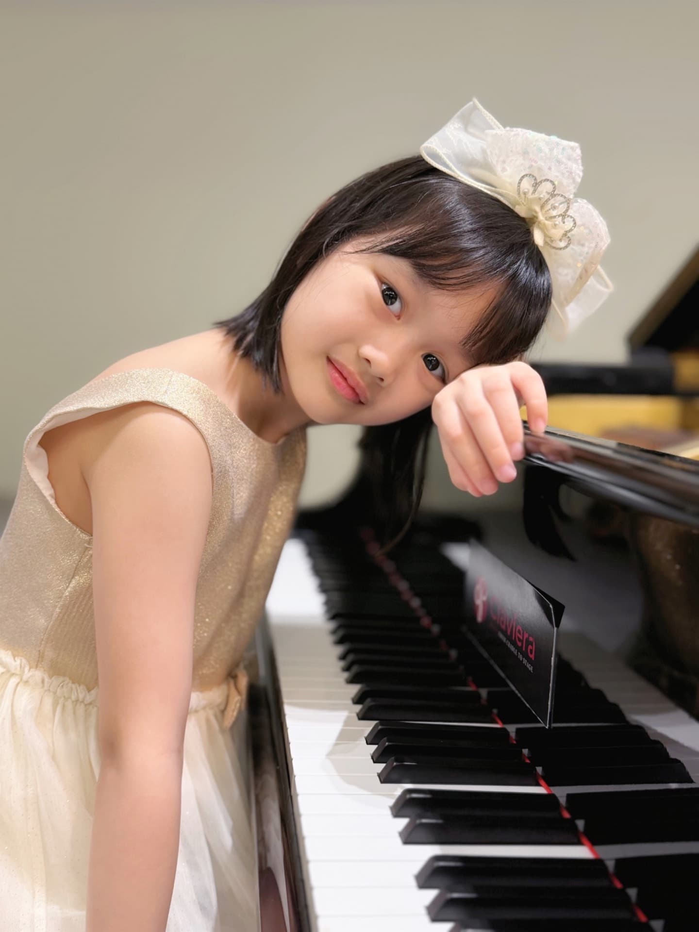 Young piano student seated beside a piano keyboard.